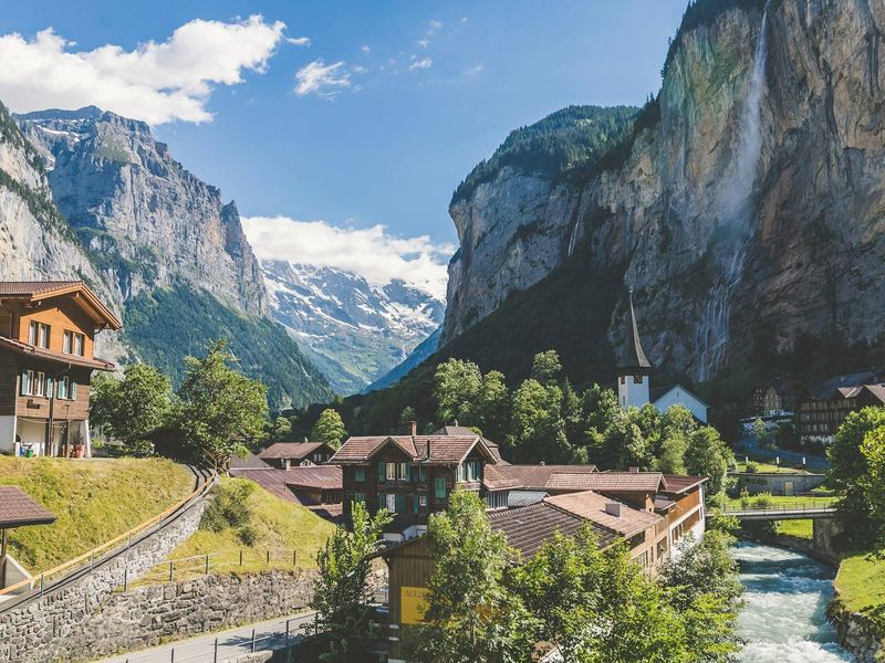 Valle alpino con cascadas y cumbres nevadas