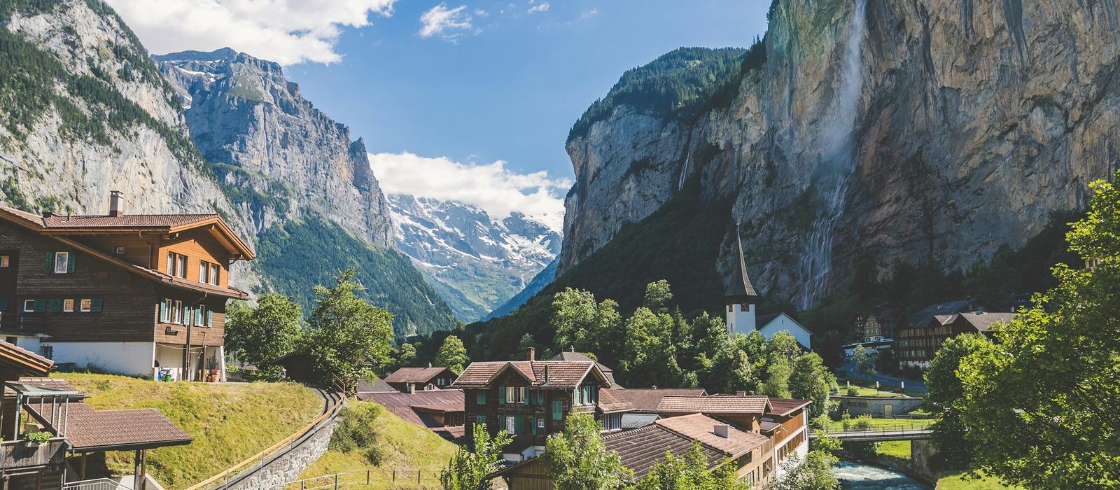 Valle alpino con cascadas y cumbres nevadas