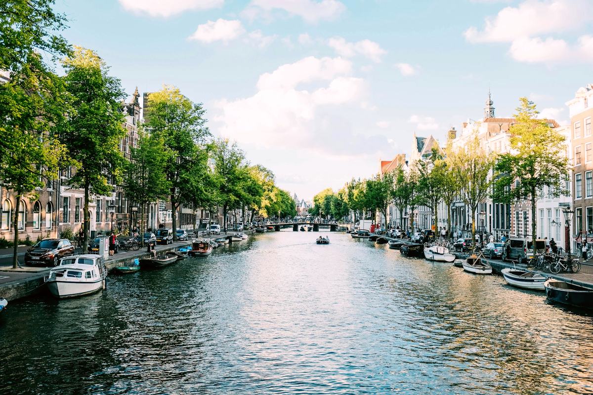 Canal de Ámsterdam con barcos amarrados y árboles